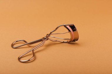 Kahverengi arka planda kirpik bigudisi. Cımbız ve takma kirpikler. Güzellik konsepti. Makyaj aleti. Mesaj için yer. Kopyalanacak yer. Mocap. FLETLEY.