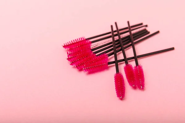 Eyelash extension brushes on a pink background. Brush for combing extended and false eyelashes. Brush for straightening eyelashes and eyebrows.