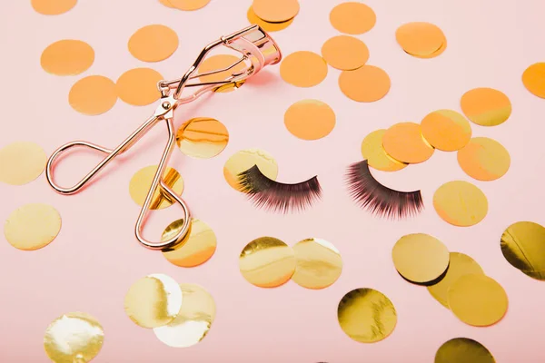 Eyelash curler on a pink background. Curling tweezers and false eyelashes. Beauty concept. Makeup tool. Place for text. Place to copy. Mocap. FLETLEY.