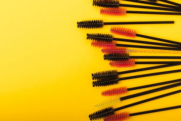 Brushes for eyelash extension on a yellow background. Brush for combing eyelashes.brush for straightening eyelashes and eyebrows.