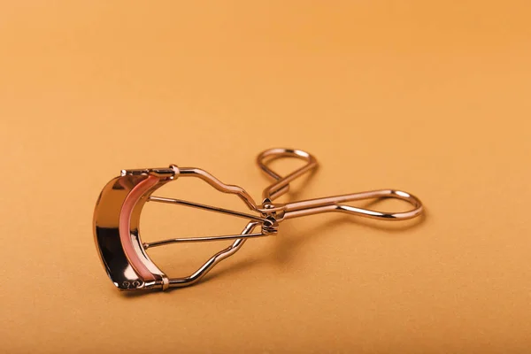 Eyelash curler on a brown background. Curling tweezers and false eyelashes. Beauty concept. Makeup tool. Place for text. Place to copy. Mocap. FLETLEY.