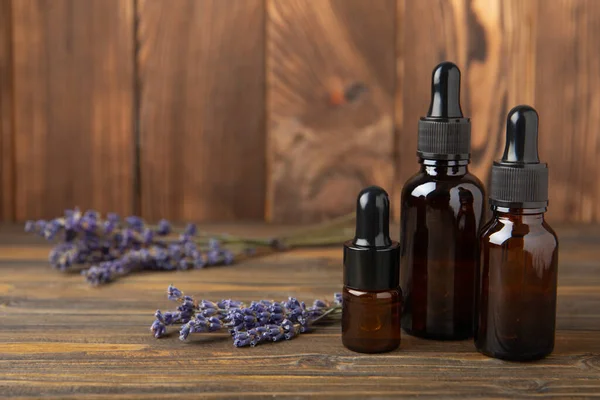 Lavender essential oil with lavender flowers on brown texture background. Aromatherapy and spa concept. Beauty. Relax.