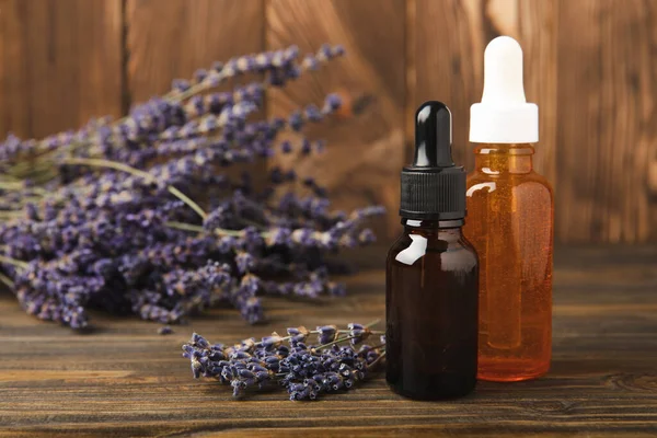 Lavender essential oil with lavender flowers on brown texture background. Aromatherapy and spa concept. Beauty. Relax.