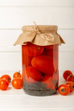 Kırsal ahşap desenli cam bir kavanozda kırmızı domates turşusu. Sonbahar ya da kış için gıda korunumu. Ev deposu. Konserve, fermantasyon konsepti. Mesaj için yer. Boşluğu kopyala.