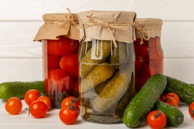 Kırsal ahşap arka planda salatalık ve domates kavanozları. Turşu ve konserve yiyecekler. Uzayı kopyala Metin için yer.