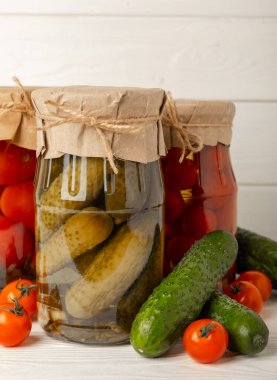 Kırsal ahşap arka planda salatalık ve domates kavanozları. Turşu ve konserve yiyecekler. Uzayı kopyala Metin için yer.