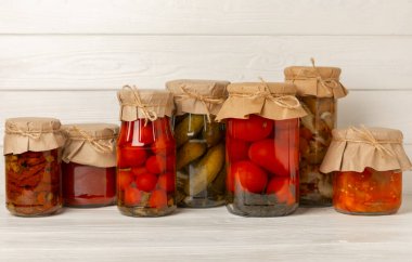 Açık dokuya sahip kavanozlar dolusu sebze, salatalık, domates, mantar ve patlıcan. Turşu ve konserve yiyecekler. Uzayı kopyala Metin için yer.