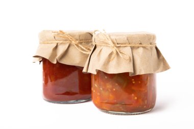 Konserve domates sosu, evde hazırlanmış ve beyaz arka planda izole edilmiş cam kavanozlarda patlıcan salatası. Turşu kavanozu..