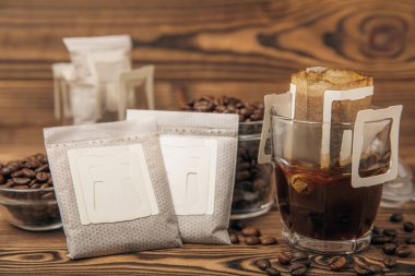 Kahverengi ahşap arka planda kullanışlı damlalı kahve filtresi olan bir bardak taze demlenmiş kahve. Evde taze demlenmiş kahve yapıyorum. Kopyalama. Mesaj için yer. Kahve yapma konsepti..