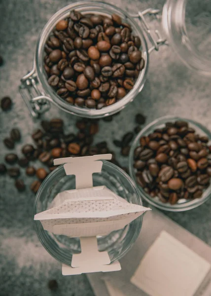 Making drip coffee with a special taste against the background of coffee beans. Drip coffee bag in a coffee cup. Trends in brewing coffee at home.Drip coffee filter. Flatley. Copy space. Place for text.