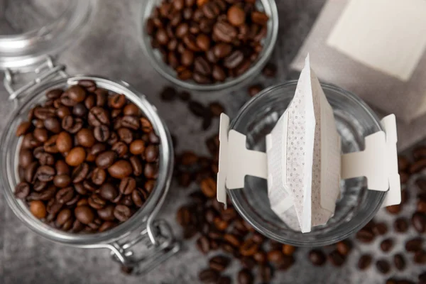 Making drip coffee with a special taste against the background of coffee beans. Drip coffee bag in a coffee cup. Trends in brewing coffee at home.Drip coffee filter. Flatley. Copy space. Place for text.