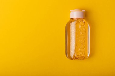 Parlak sarı arka planda Micellar suyu. Makyaj ve sebum silme toneri. Tonik, serum ya da losyon. Cilt bakımı. Güzellik konsepti. FLETLEY. Süper manzara. Mesaj için yer. Boşluğu kopyala