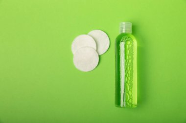 Yeşil arka planda Micellar su ve pamuk pedleri. Makyaj ve sebum silme toneri. Tonik, serum ya da losyon. Cilt bakımı. Güzellik konsepti. FLETLEY. Süper manzara. Mesaj için yer. Boşluğu kopyala