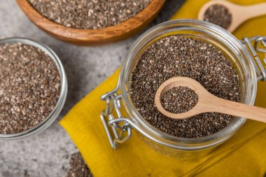 Kaşık içinde Chia tohumu ve siyah dokuda kase. Süper yiyecek ve aksiyoner. Diyet olsun. Yakın plan. Mesaj için yer. Boşluğu kopyala.