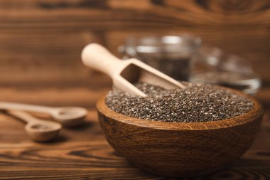Tahta kaşıkta Chia tohumu ve kahverengi desenli bir masada kase. Süper yiyecek ve aksiyoner. Diyet olsun. Yakın plan. Mesaj için yer. Boşluğu kopyala.