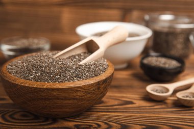 Tahta kaşıkta Chia tohumu ve kahverengi desenli bir masada kase. Süper yiyecek ve aksiyoner. Diyet olsun. Yakın plan. Mesaj için yer. Boşluğu kopyala.