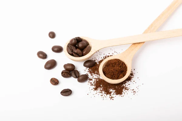 Ground coffee and coffee beans in wooden spoons isolated on white background.