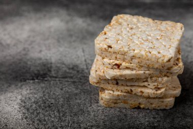 Siyah desenli arka planda bir yığın çıtır pirinç keki. Diyet ekmek. Diyet olsun. Düzgün beslenme. GLUTEN ÖZGÜR. Uzayı kopyala Metin için yer.