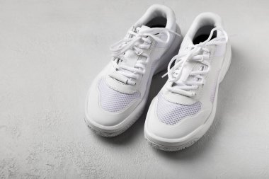 Gri çimento arka planda beyaz şık uniseks spor ayakkabıları. Ayakkabı modası. Düz çizgi. Rahat spor ayakkabıları..