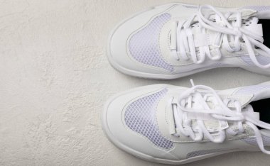 Gri çimento arka planda beyaz şık uniseks spor ayakkabıları. Ayakkabı modası. Düz çizgi. Rahat spor ayakkabıları..