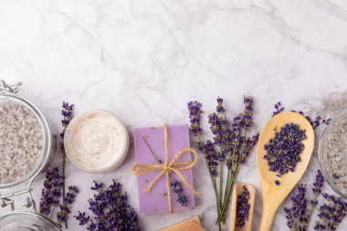 Spa lavantası. Beyaz mermer arka planda deniz tuzu, vücut kremi ve el yapımı sabun. Lavanta çiçekli doğal kozmetik ürünleri. Relak ve rahatlama. Aromaterapi. güzellik konsepti