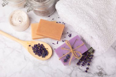 Spa lavantası. Beyaz mermer arka planda deniz tuzu, vücut kremi ve el yapımı sabun. Lavanta çiçekli doğal kozmetik ürünleri. Relak ve rahatlama. Aromaterapi. güzellik konsepti