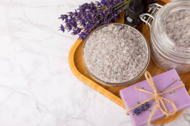 Spa lavantası. Deniz tuzu, temel yağlar ve beyaz mermer arka planda el yapımı sabun. Lavanta çiçekli doğal kozmetik ürünleri. Relak ve rahatlama. Aromaterapi. güzellik konsepti