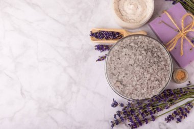 Spa lavantası. Beyaz mermer arka planda deniz tuzu, vücut kremi ve el yapımı sabun. Lavanta çiçekli doğal kozmetik ürünleri. Relak ve rahatlama. Aromaterapi. güzellik konsepti