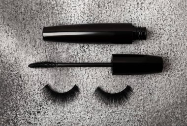 Composition with mascara and false eyelashes on a black marble background. Beauty concept. Makeup kit. Makeup. Place for text. Copy space. Close-up. FLETLEY