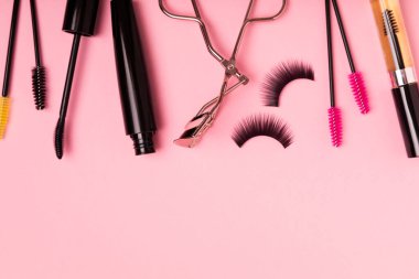 Composition with curlers, mascara and false eyelashes on a pink background. Beauty concept. Makeup kit. Makeup. Place for text. Copy space. Close-up. FLETLEY