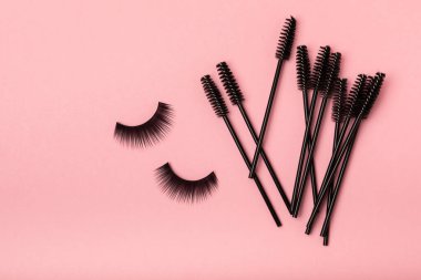 False eyelashes and an eyelash brush on a pink background close-up. Makeup. Beauty concept. Beautiful long eyelashes in a beauty salon