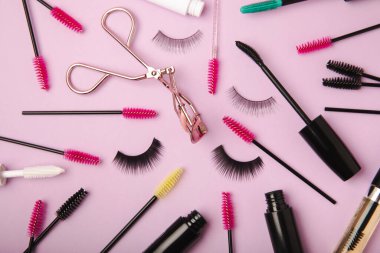 Composition with curlers, mascara and false eyelashes on a pink background. Beauty concept. Makeup kit. Makeup. Place for text. Copy space. Close-up. FLETLEY