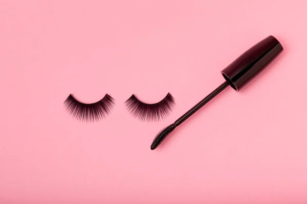 Composition with mascara and false eyelashes on a pink background. Beauty concept. Makeup kit. Makeup. Place for text. Copy space. Close-up. FLETLEY