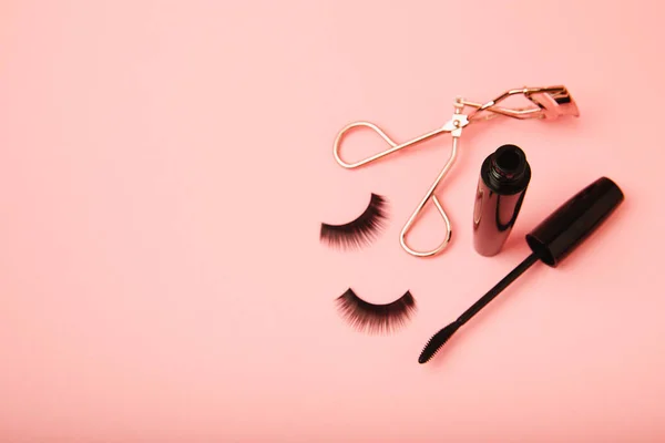 Composition with curlers, mascara and false eyelashes on a pink background. Beauty concept. Makeup kit. Makeup. Place for text. Copy space. Close-up. FLETLEY