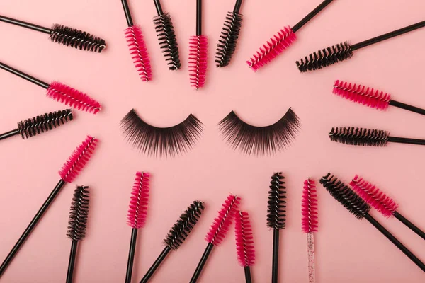False eyelashes and an eyelash brush on a pink background close-up. Makeup. Beauty concept. Beautiful long eyelashes in a beauty salon