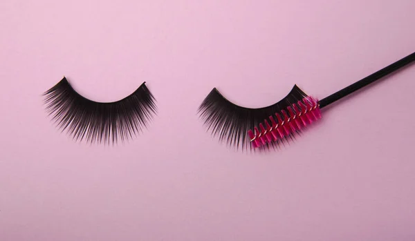 False eyelashes and an eyelash brush on a lilac background close-up. Makeup. Beauty concept. Beautiful long eyelashes in a beauty salon