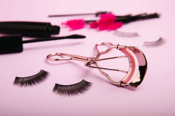 Eyelash curler, false eyelashes and mascara on a pink background. Beauty concept. Makeup. Place for text. Copy space.