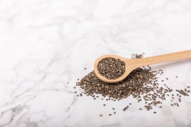 Chia seeds in a wooden spoon on a marble table. Superfood. Proper nutrition. Diet. Healthy food. Place for text. Place to copy.