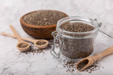 Bowl and spoon with chia seeds on a white marble table. Superfood. Proper nutrition. Diet. Healthy food. Place for text. Place to copy.