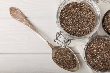 Bowl and spoon with chia seeds on a white wooden table. Superfood. Proper nutrition. Diet. Healthy food. Place for text. Place to copy.
