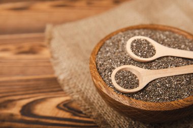 Chia seeds in a bowl and spoons on a brown textural background. Superfood. Proper nutrition. Diet. Healthy food. Place for text. Place to copy.