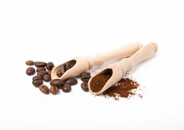 Ground coffee and beans in wooden spoons isolated on white background.