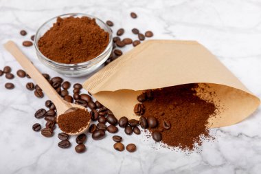 Coffee filter, drip brewing. Manual coffee brewing. Coffee beans and ground coffee on white marble. The concept of brewing a drink.