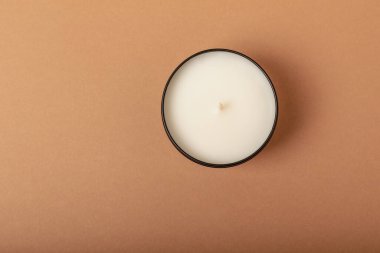 Soy candle in a black candlestick on a brown background. Space for text. Decor.
