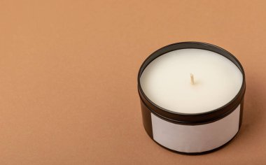 Soy candle in a black candlestick on a brown background. Space for text. Decor.
