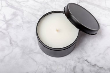 Soy candle in a black candlestick on a marble background. Space for text. Decor.