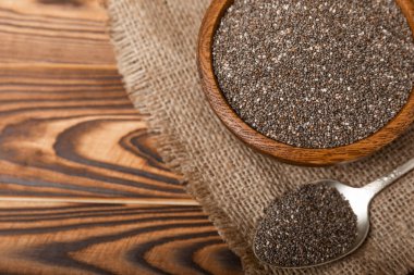 Chia seeds in bowl and spoons on brown wood texture. Diet food. Superfood. Healthy food. Space for text, copy space