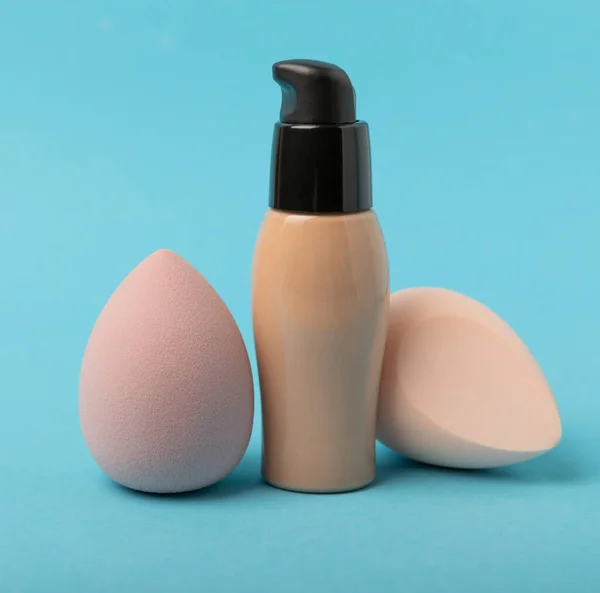 Beauty blender and tannal cream, concealer on a blue background. Bright sponges for cosmetics. Makeup products. Beauty concept. Place for text. Place to copy. flat lay