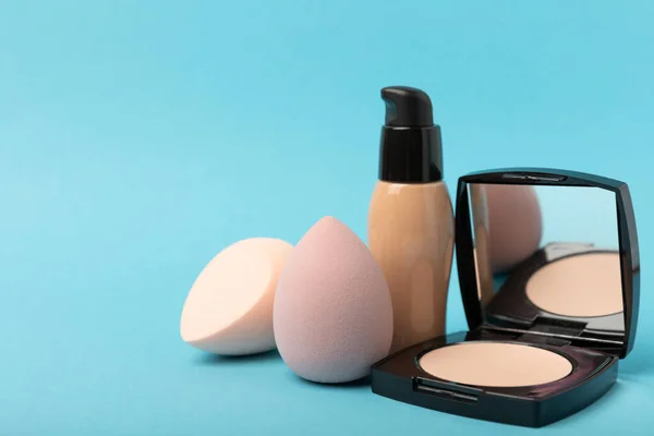 Beauty blender and tannal cream, concealer and shadows on a blue background. Bright sponges for cosmetics. Makeup products. Beauty concept. Place for text. Place to copy. flat lay