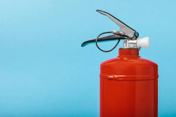Fire extinguisher on the background of a blue wall. Fire protection, home fire extinguisher. home security concept. Place for text. Copy space.